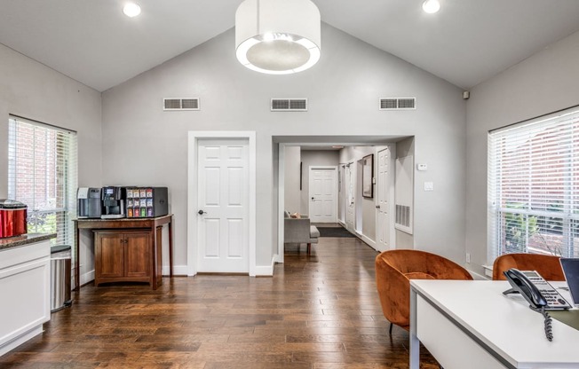 an office with a desk and a chair and a hallway with a door and windows