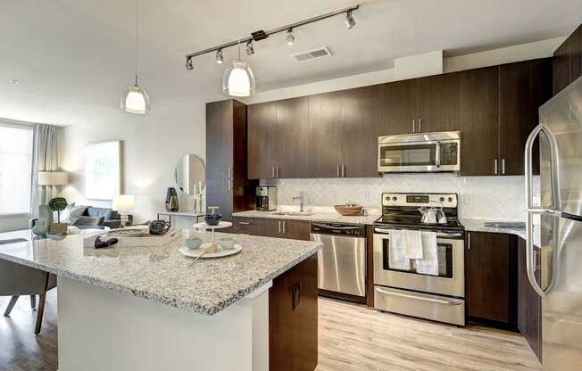 A modern kitchen with a granite countertop and stainless steel appliances.