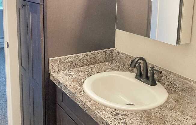 A bathroom sink with a granite counter top and a silver faucet.