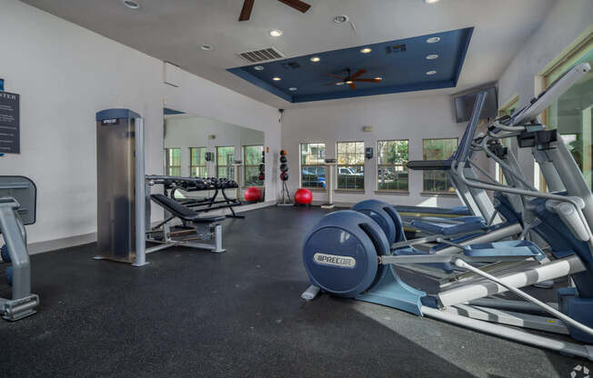 A gym with a variety of equipment including a treadmill, a stationary bike, and a rowing machine.