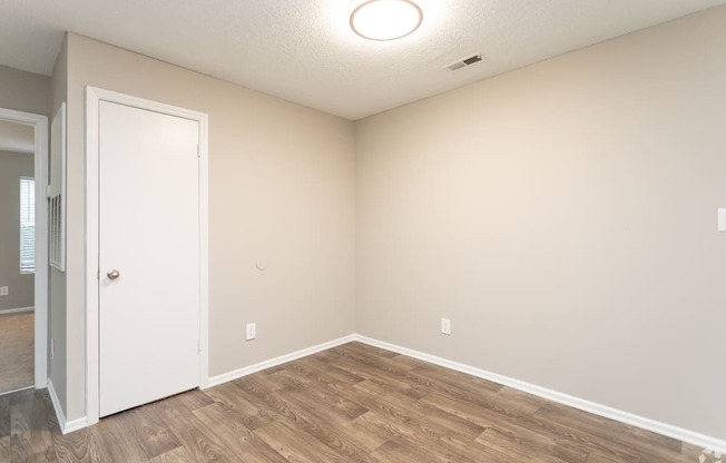 an empty room with wood flooring and a white door