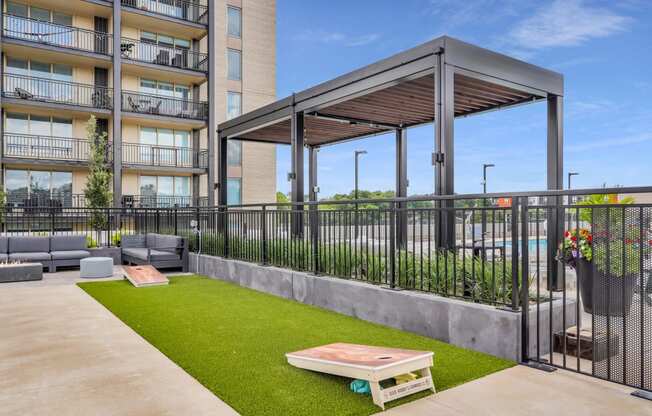 a patio with a table and chairs and a pergola in front of an apartment building