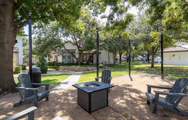 A park with a table and chairs under a tree.