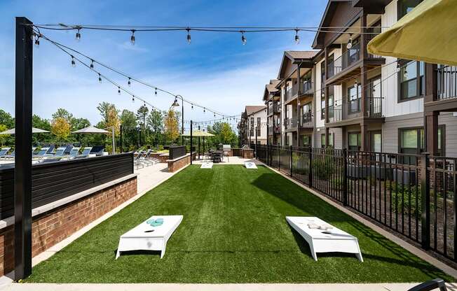 a grassy courtyard with two white tables and a fence