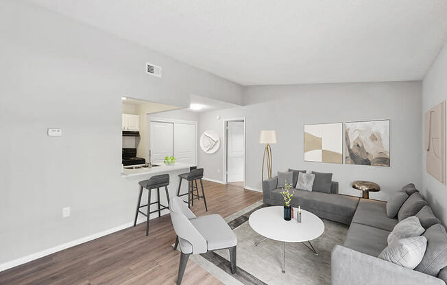 Model Living Room with Wood-Style Flooring and View of Kitchen at Vue at Baymeadows Apartments in Jacksonville, FL.