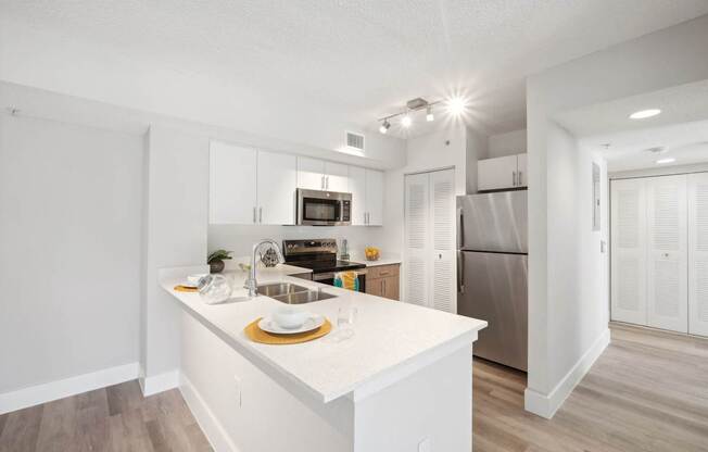 A kitchen with white cabinets and a white island.