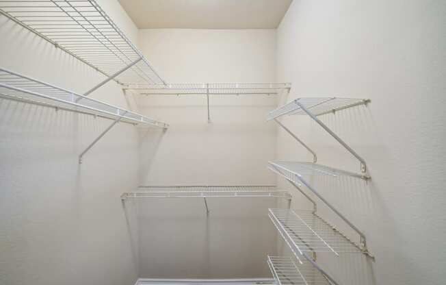 a walk in closet with white walls and metal stairs