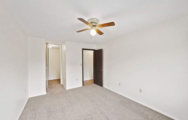 a bedroom with white walls and a ceiling fan
