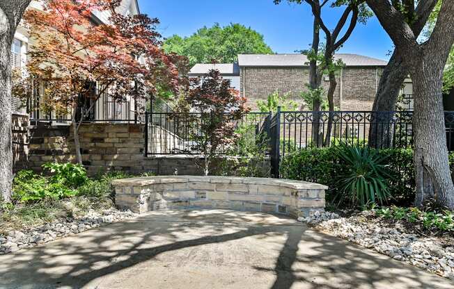 a retaining wall with a stone bench in front of a black wrought iron fence