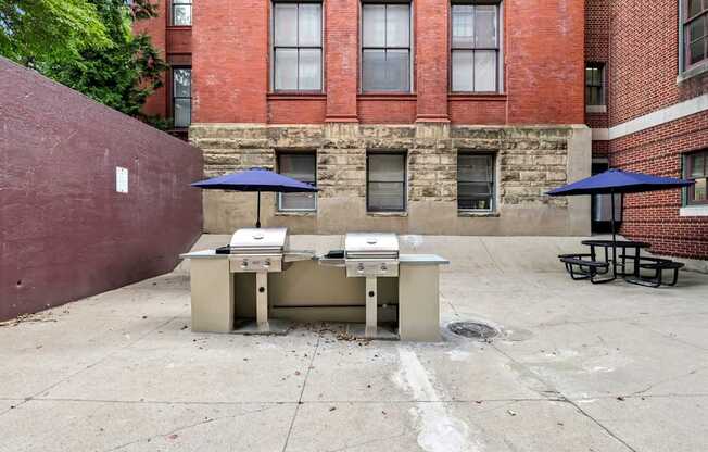 Picnic tables and umbrellas are set up on a concrete patio.