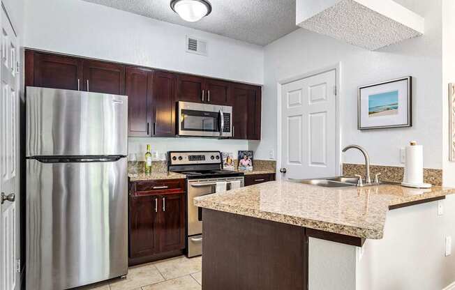 a kitchen with stainless steel appliances and a granite counter top at Waterford Park Apartment Homes, LLC, Florida