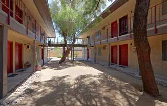 a courtyard with trees and red doors