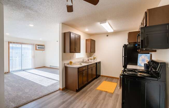 the view of a kitchen and living room with a sliding glass door. Fargo, ND Eagle Run Apartments