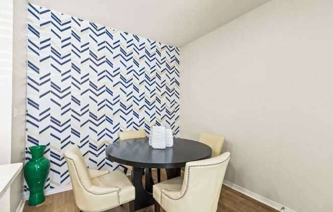 a dining room with a table and chairs and a wall with a geometric wallpaper
