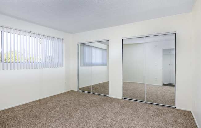 an empty bedroom with mirrored closet doors and carpeting