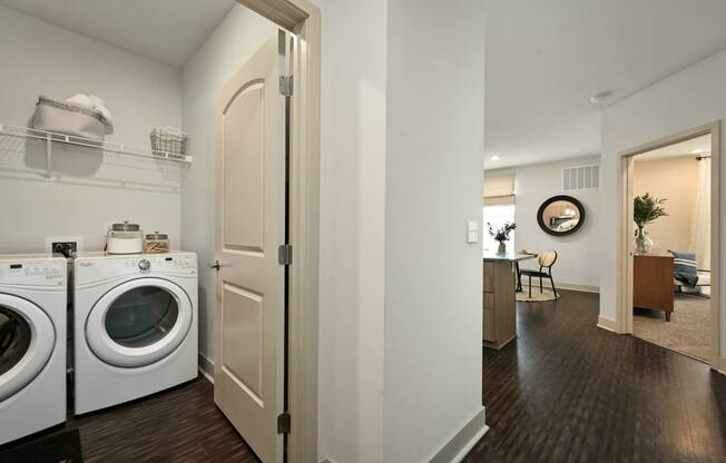 a washer and dryer in a living room with a laundry room door open