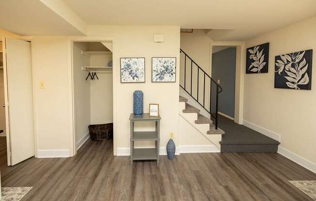 A hallway with a staircase and a table with objects on it.