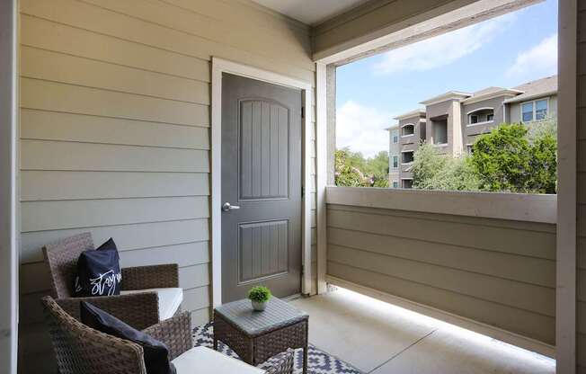 A patio with a chair and a table with a plant on it.