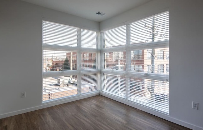 an empty living room with large windows and wood floors