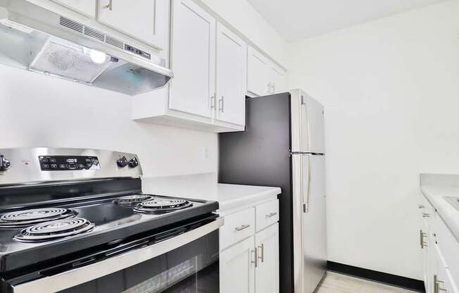 a kitchen with white cabinets and black appliances and a refrigerator