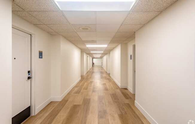 a hallway with white walls and wooden floors and doors