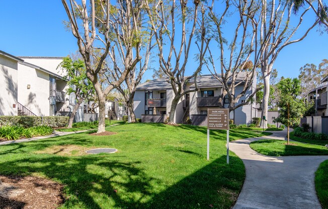 A sign in a grassy area in front of a building.
