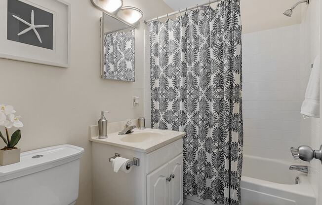 a bathroom with white fixtures and a black and white shower curtain