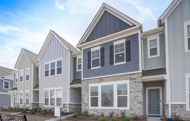 a row of townhomes with gray siding and a gray door