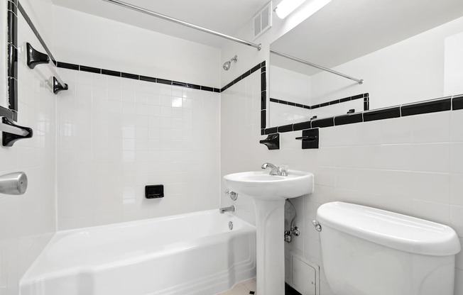 A white bathroom with a tub, sink, and toilet.