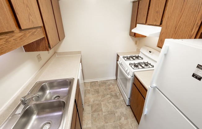 2 bedroom apartment kitchen with white appliances and brown cabinets at Woodbridge Apartments