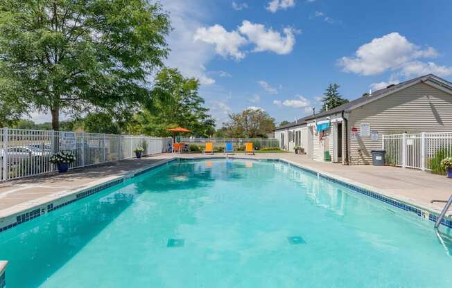 A large swimming pool surrounded by a fence and trees.