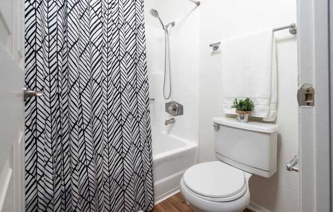 A bathroom with a white toilet and a black and white shower curtain.