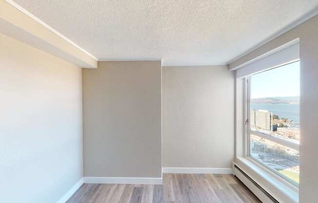 an empty room with a large window and hardwood floors