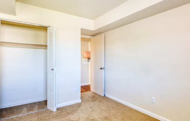 an empty bedroom with a closet and a hallway to a bathroom