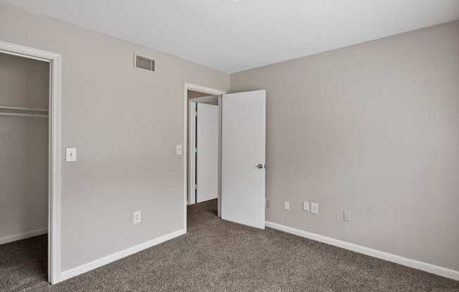 an empty room with carpet and a door to a closet