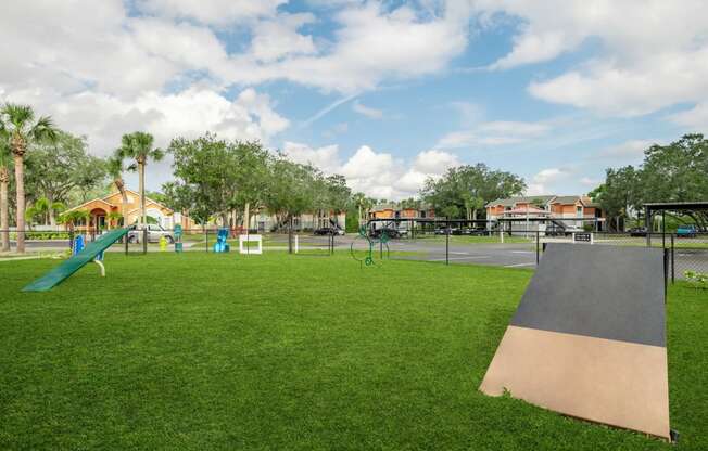 a playground with a slide and trampoline at the whispering winds apartments in pearland,