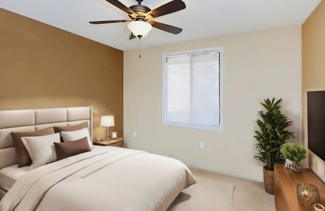 A bedroom with a large bed and a ceiling fan.