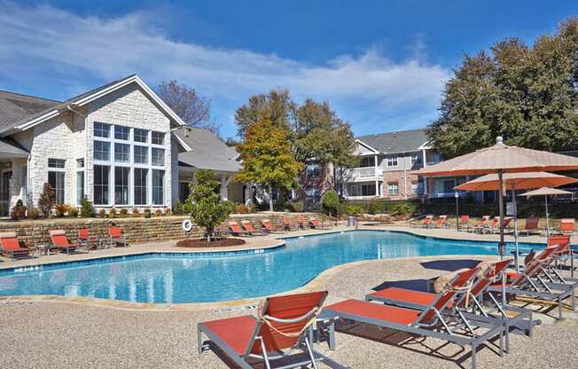 a swimming pool with chairs and umbrellas in front of a houseat Creekside at Legacy, Plano, TX