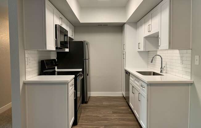 an empty kitchen with white cabinets and a black refrigerator