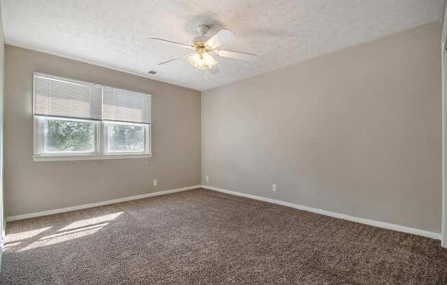 Omaha, NE Maple Ridge Apartments. A bedroom with a ceiling fan and two windows