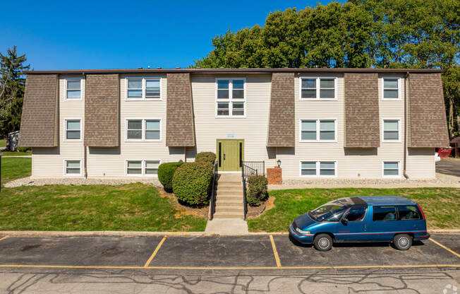 an apartment building with a blue van parked in front of it