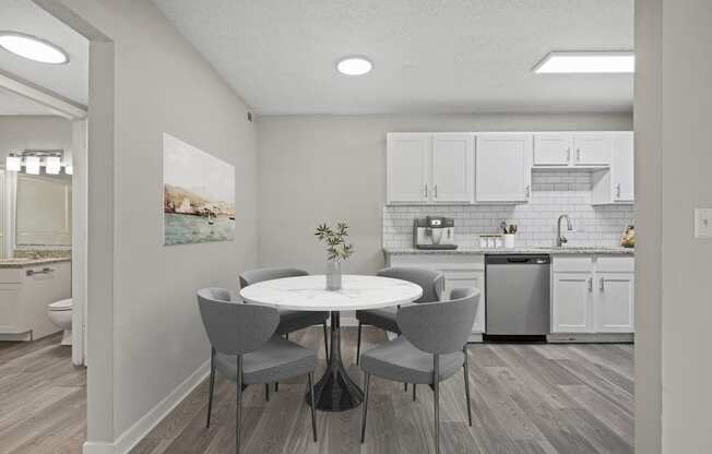 a dining area with a table and chairs and a kitchen in the background