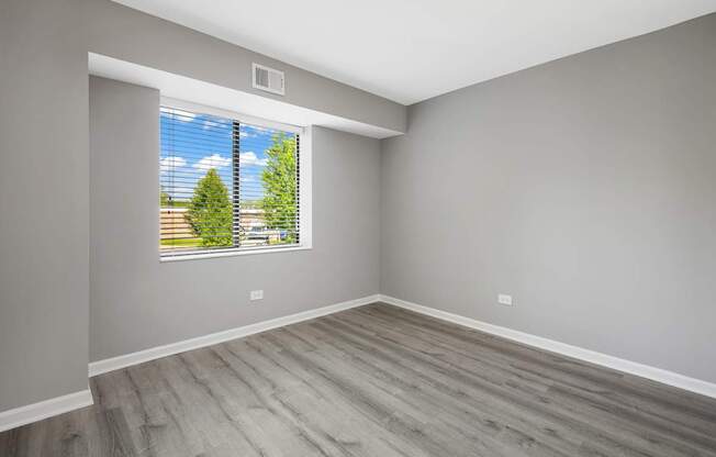 A room with a window showing a tree and sky.