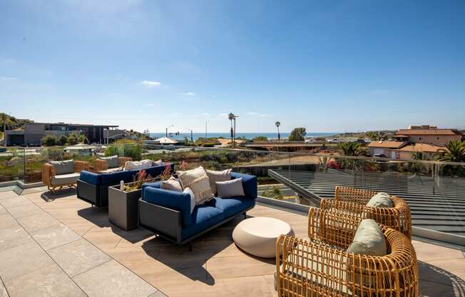 a roof deck with couches and chairs overlooking the ocean