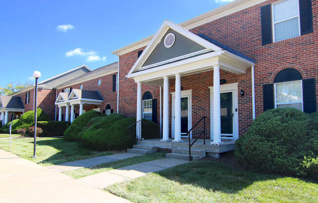 A red brick house with a white front porch.