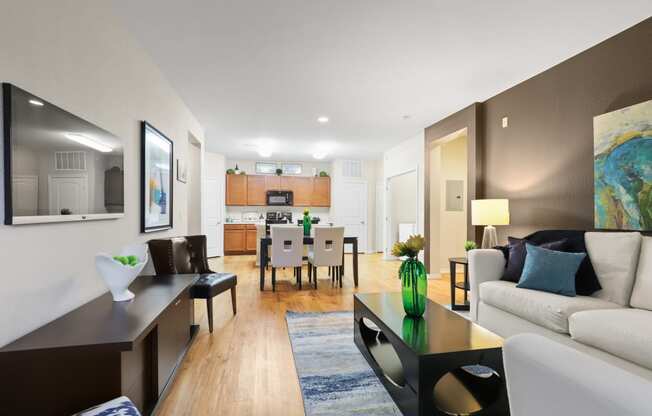 a living room with a couch coffee table and a dining room table in the background