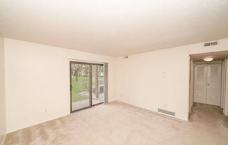 A  living room with a sliding glass door leading to a patio at Madeira Apartments in Kalamazoo, MI