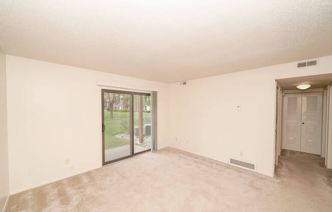 A  living room with a sliding glass door leading to a patio at Madeira Apartments in Kalamazoo, MI