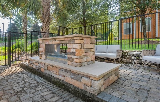 Tallahassee FL apartment complex grilling pavilion with two grills, lounge chairs, brick flooring, and a roofed sitting area at Evergreens at Mahan