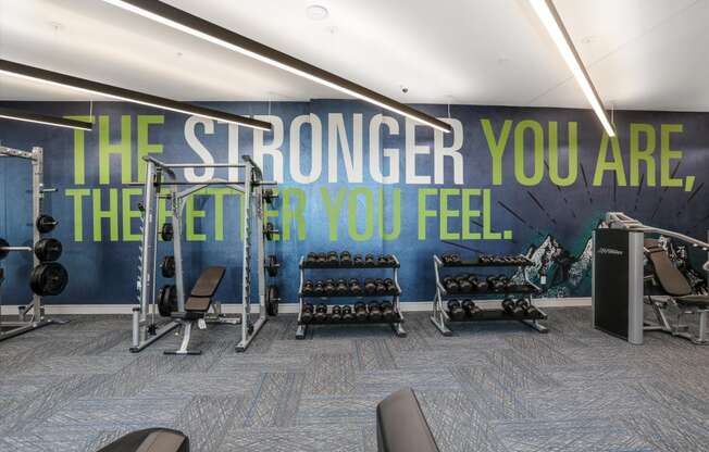 a fitness room with a wall mural that says the stronger you are the fit you